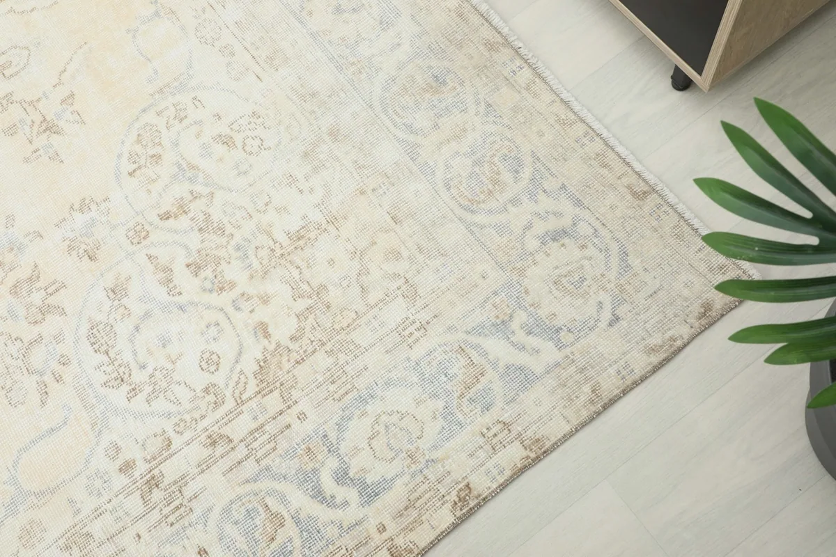 Angled view of the rug's corner, revealing the intricate border design and gentle color variations.