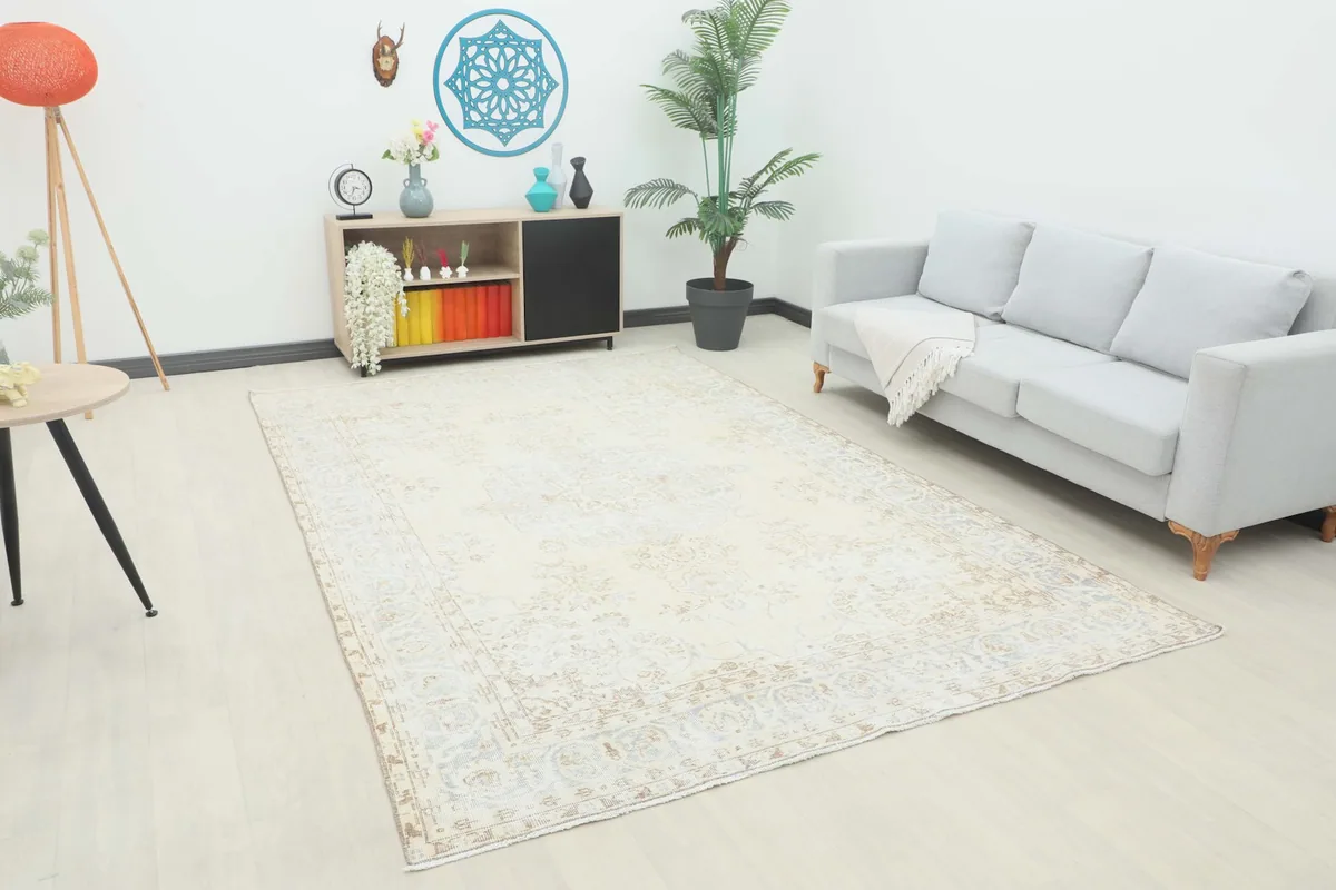 Ivory area rug displayed in a living room setting with a light gray sofa and wooden furniture.