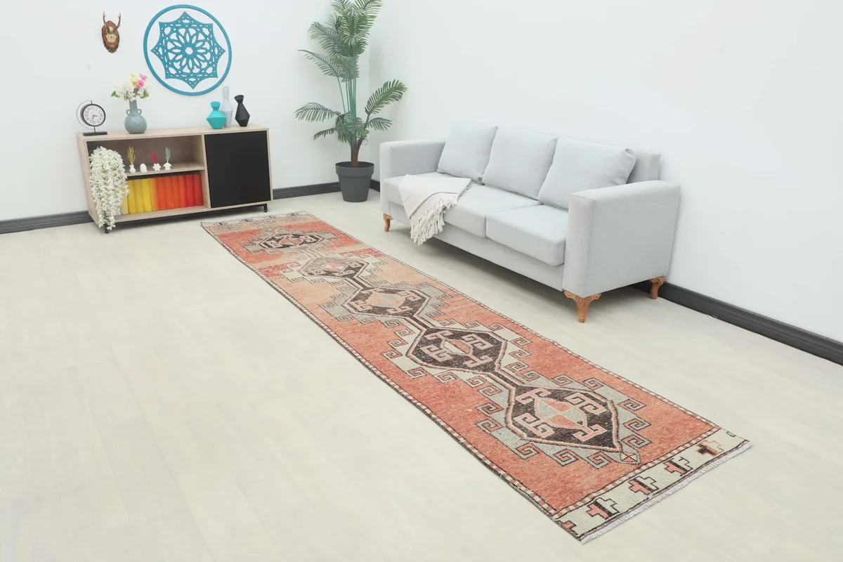 Vintage runner rug displayed in a room setting with a light gray sofa and plant