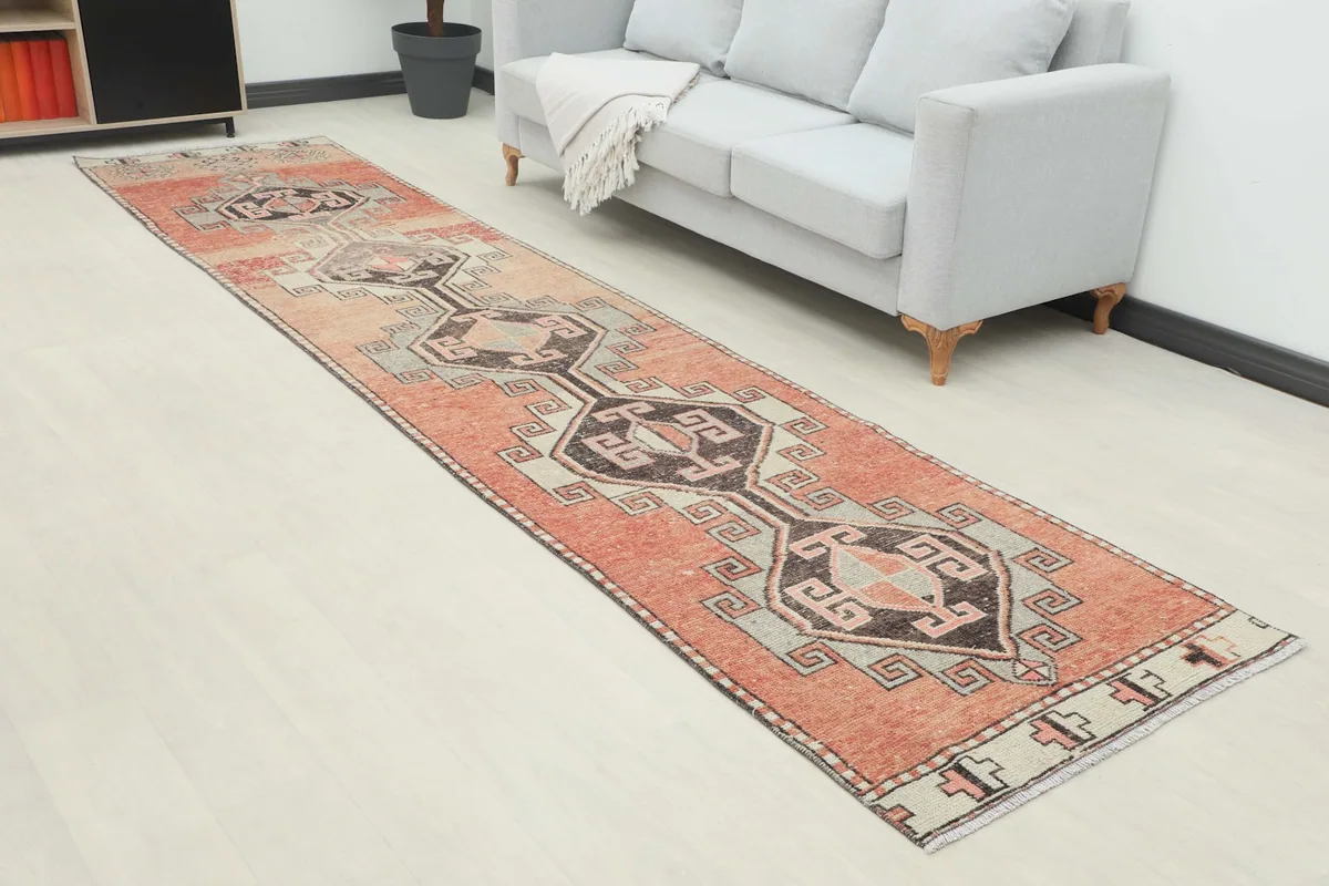 Angle view of the rust and gray geometric runner rug in a long hallway setting