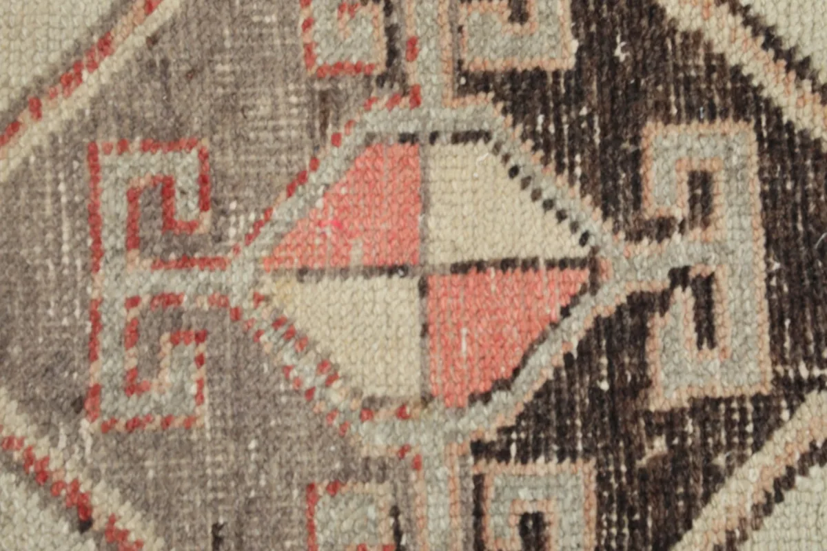 Macro view showing the low wool pile texture and color variations of the vintage rug