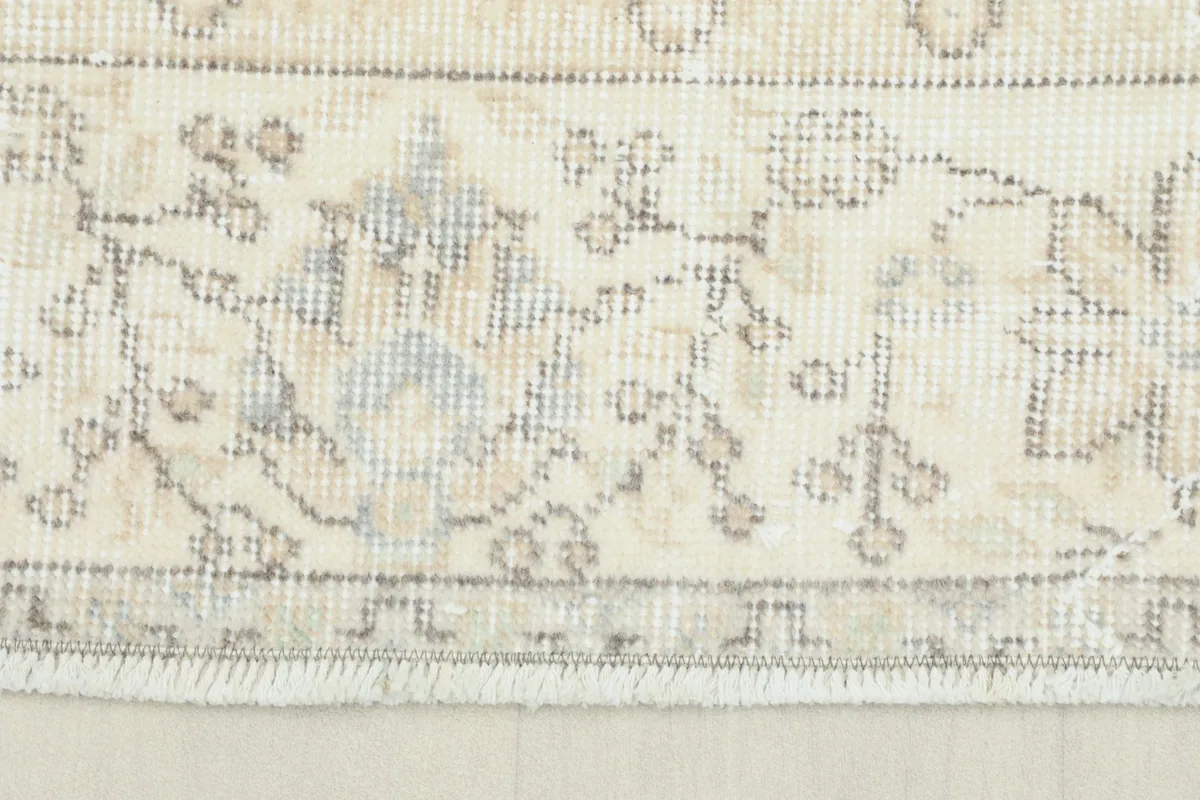 Close-up detail of the rug's subtle floral patterns and fringe along one edge