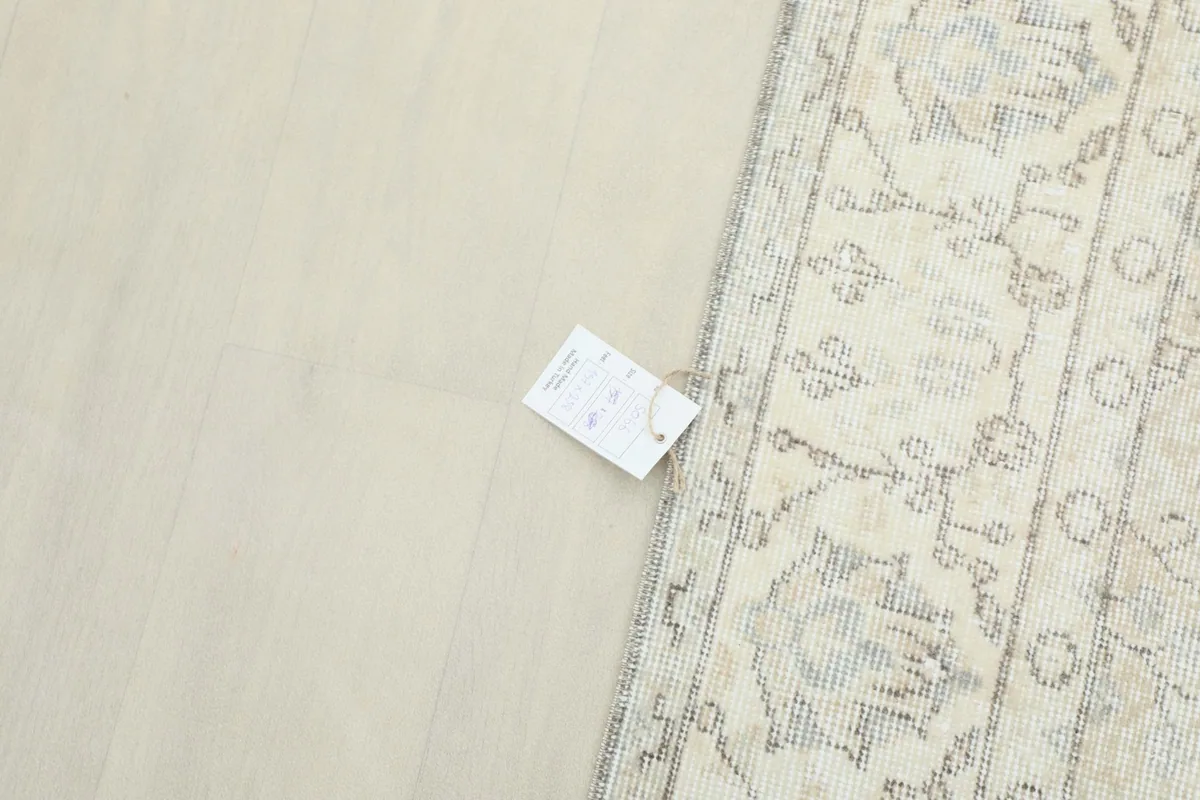 View of the rug's reverse side near the edge, showing the hand-knotted foundation and care tag
