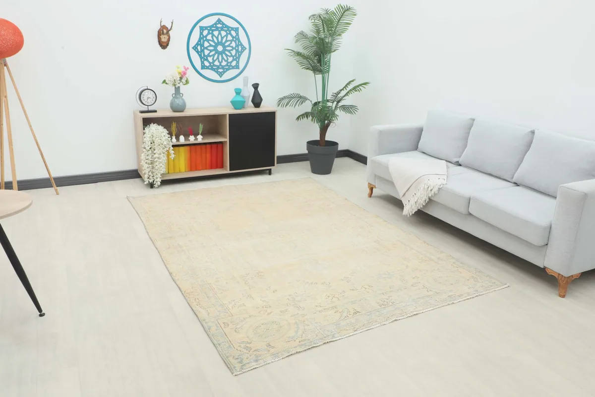 Angle view of the beige and blue vintage rug in a living room setting with a light gray couch