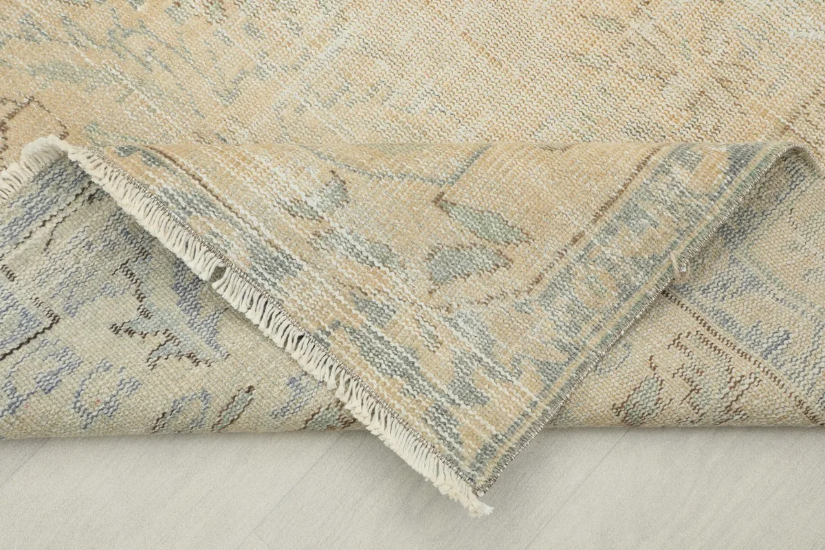 Folded corner of the rug revealing the cotton foundation and the reverse side of the hand-knotted wool