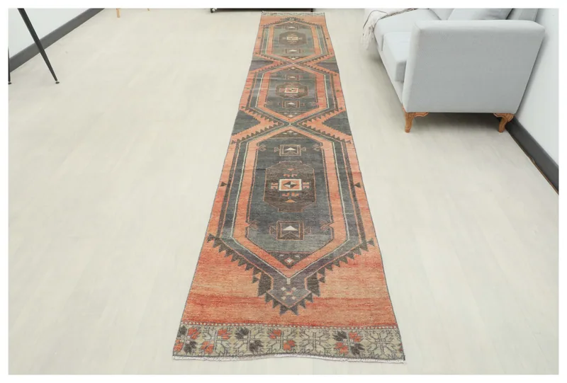 Full overhead view of the charcoal and rust geometric vintage runner rug on a white floor