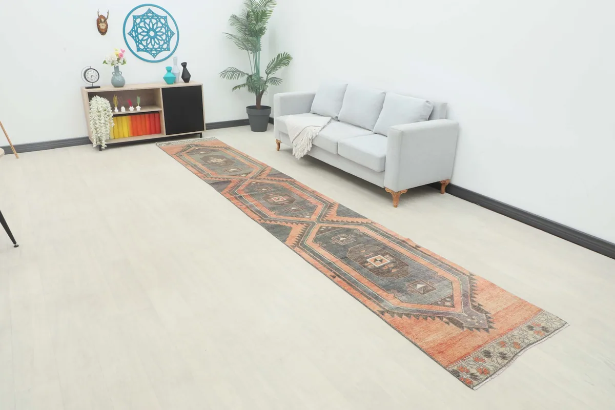 Vintage runner rug displayed in a room setting next to a gray sofa and console table