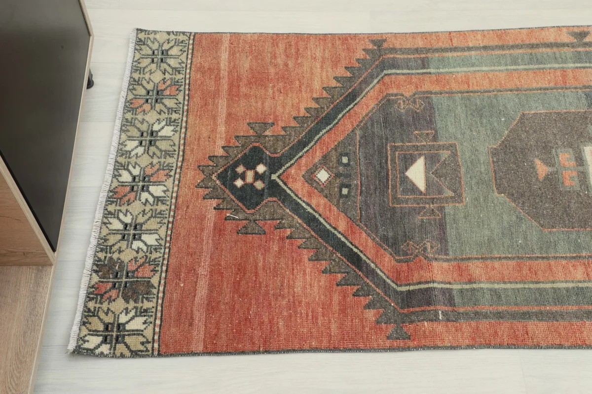 Detail view of the rug's end, showcasing the patterned border and color variation