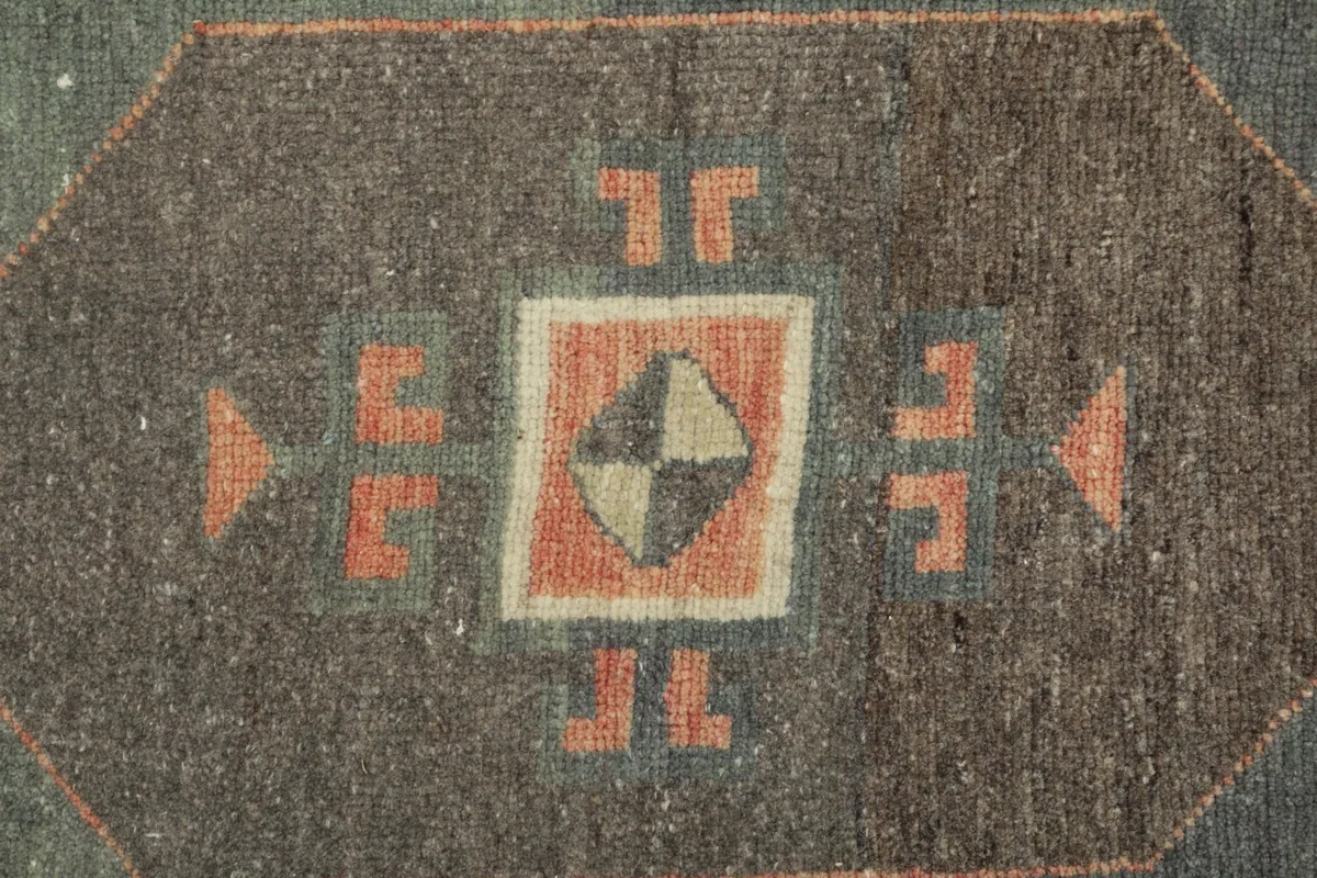 Detailed shot of a central geometric motif within the charcoal field, showing wool texture