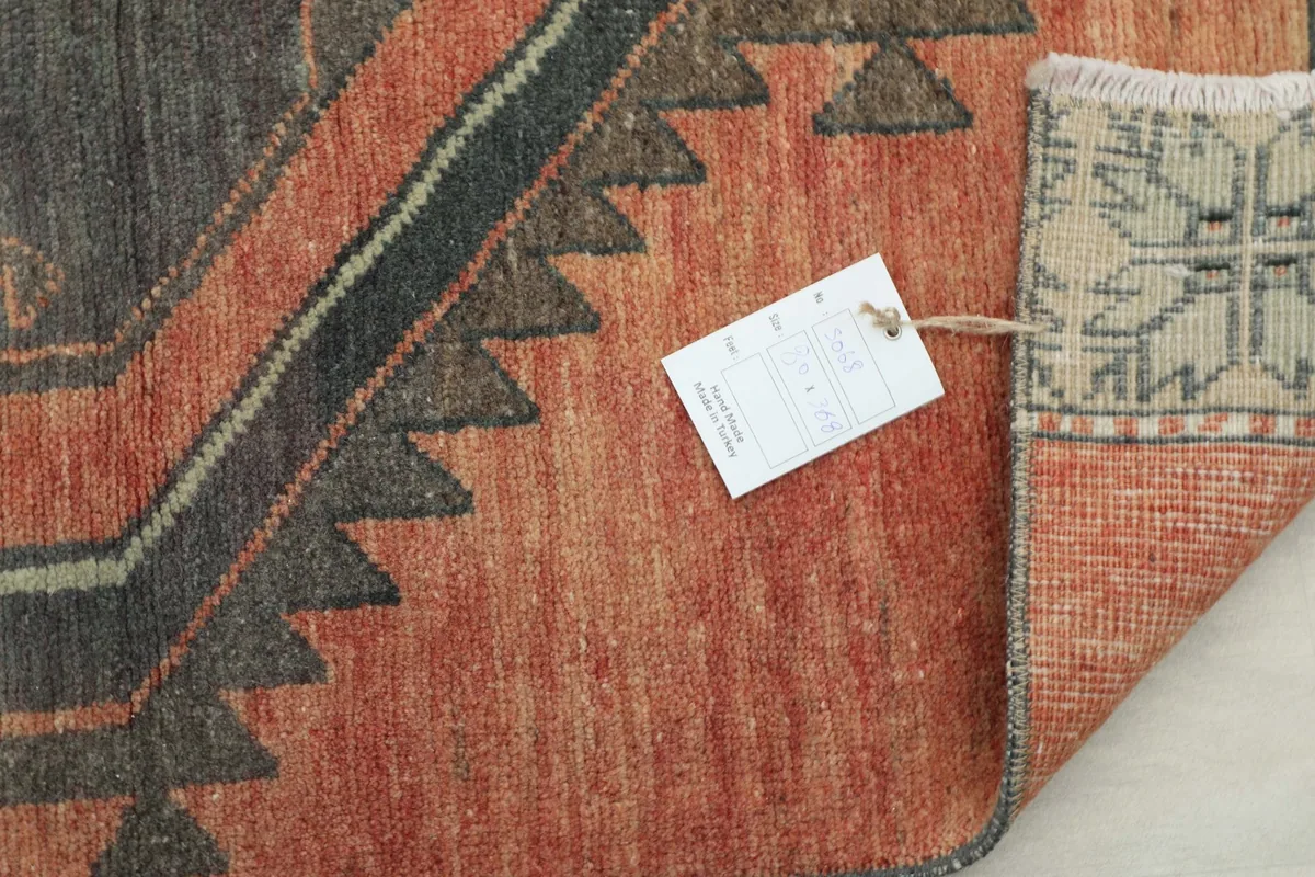 Close-up of the rug's end with a tag, showing the fringe and a section of the border