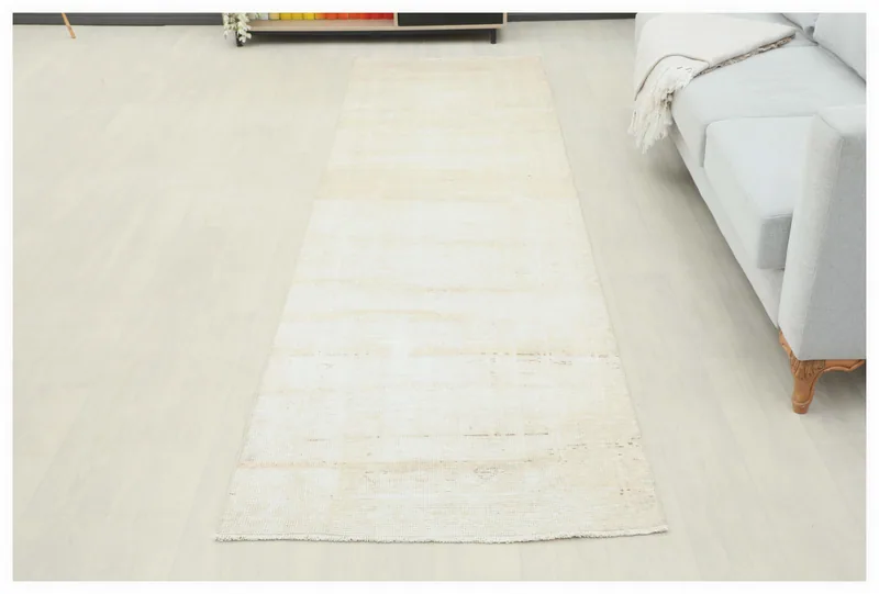 Full top view of a beige hand-knotted vintage Anatolian runner rug on a white floor.