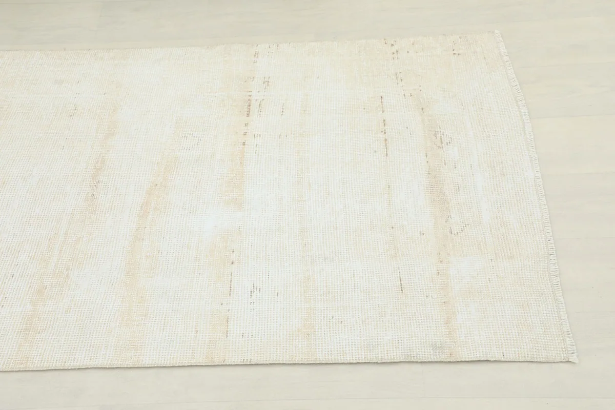 Close-up detail of the faded beige pile and subtle texture of the vintage runner rug.