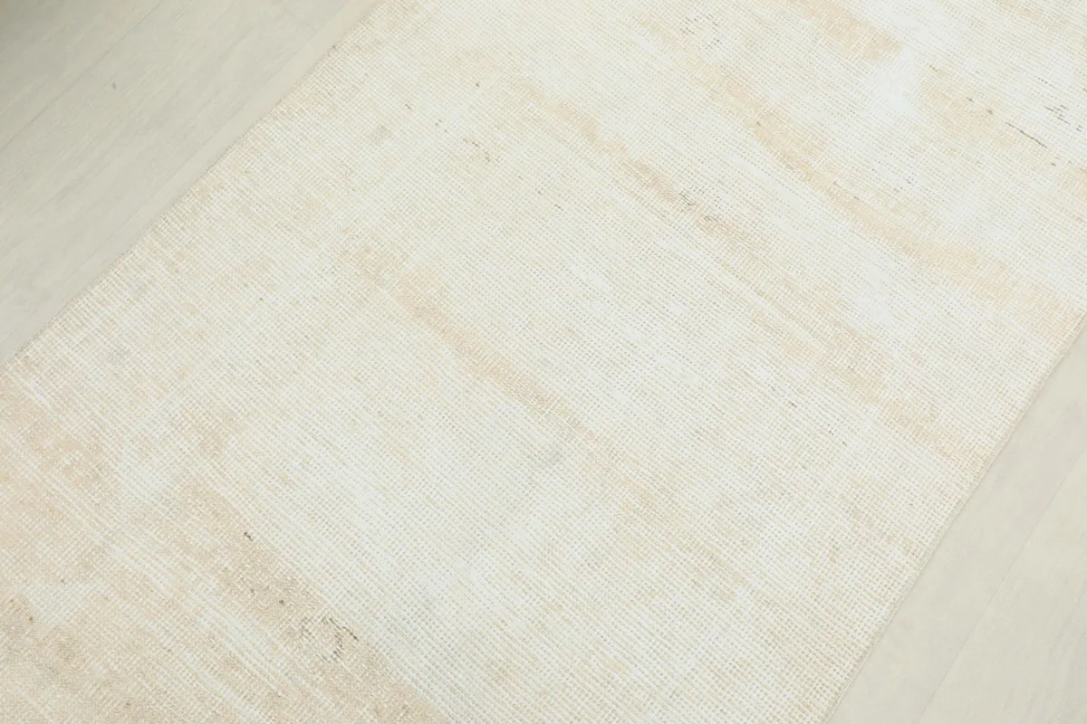 Detailed view of the distressed beige surface, showing variations in color and pile.