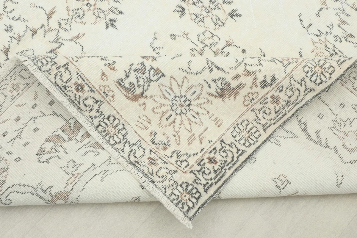 Folded corner of the rug, revealing the cotton foundation and the reverse side of the knots.