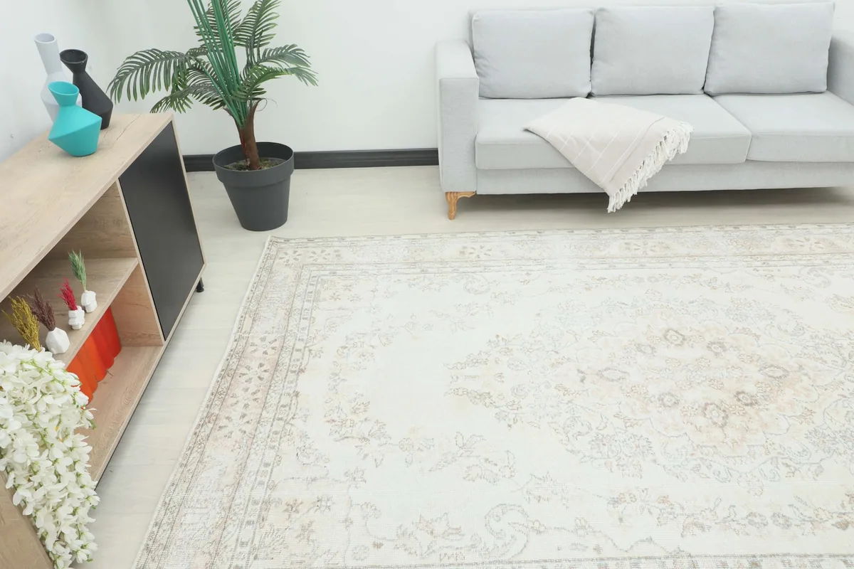 Angle view of the ivory and beige vintage rug in a living room setting, complementing a light-colored sofa.