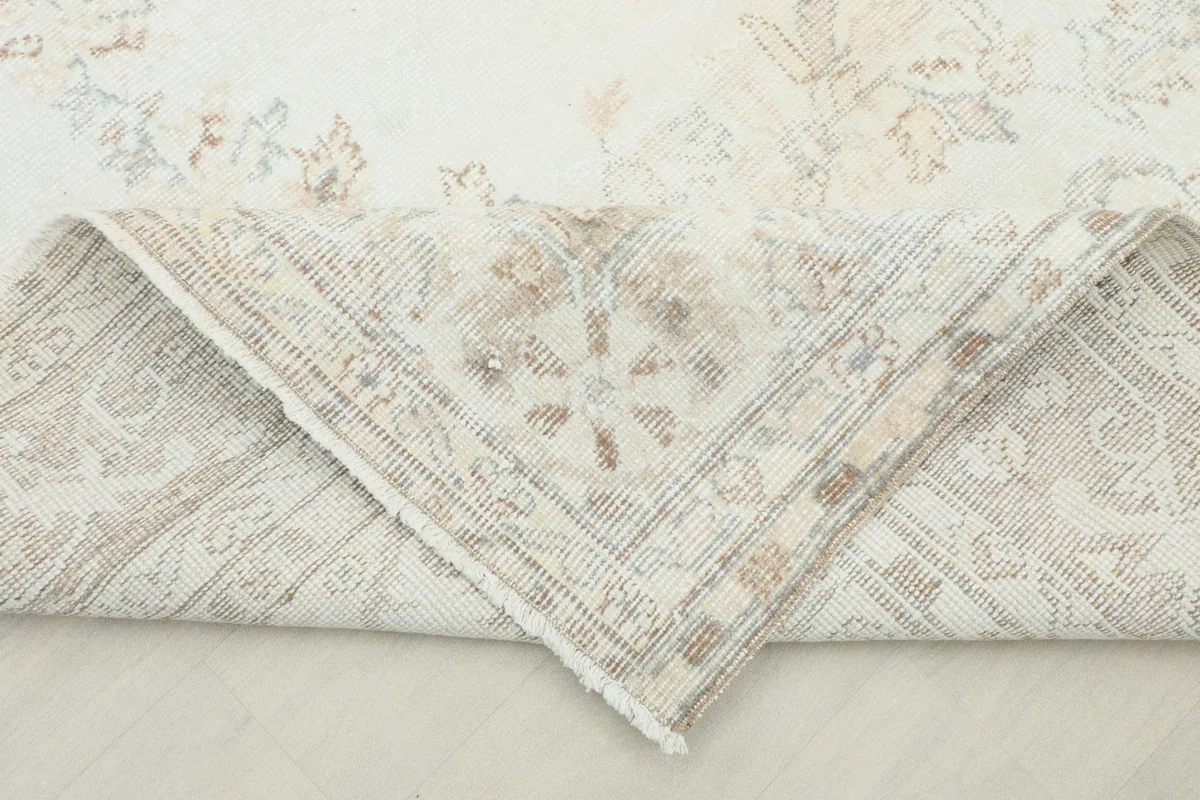 A folded corner of the rug revealing the cotton foundation and the reverse side of the hand-knotted construction.
