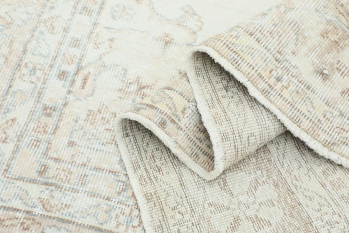 Close-up of the rug's folded edge, highlighting the vintage wool pile and the subtle variations in color.