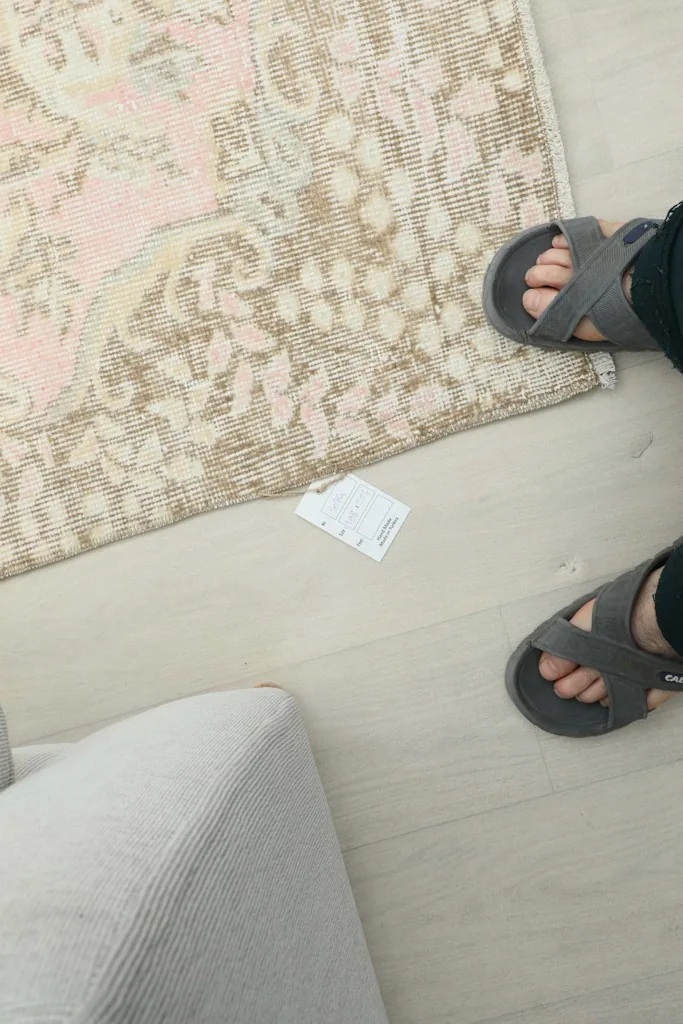Close-up of the rug's texture and color variation on the floor next to feet
