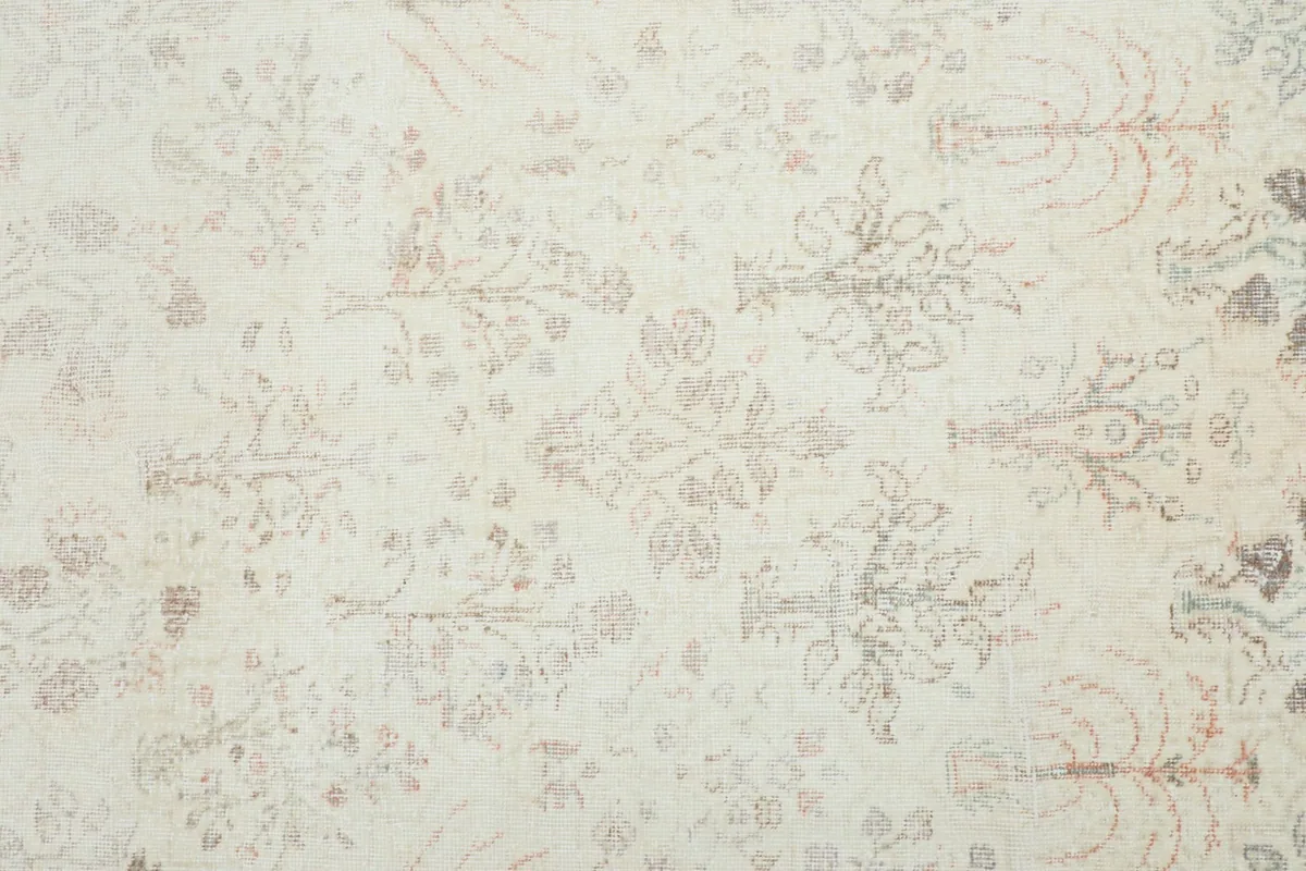 Detailed view of the subtle floral and geometric motifs within the ivory field