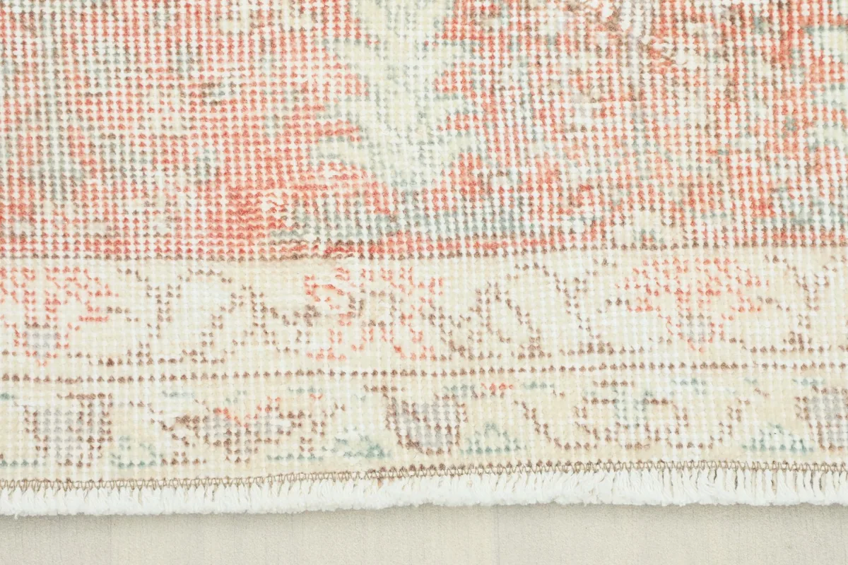 Close-up view of the faded red border and ivory field with floral patterns