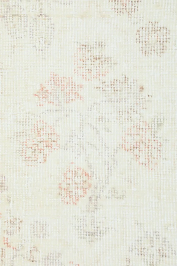 Close-up texture of the low wool pile showing faded colors and hand-knotted weave