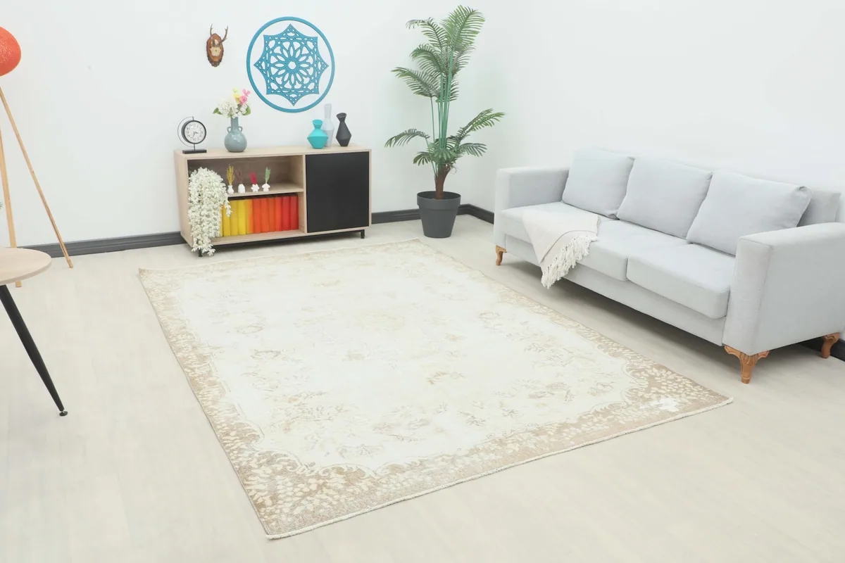 Vintage cream and beige rug laid out in a modern living room setting with a gray sofa.