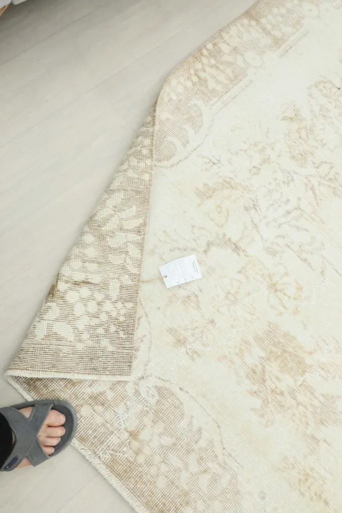 Underside of the rug with a tag, showing the hand-knotted construction.