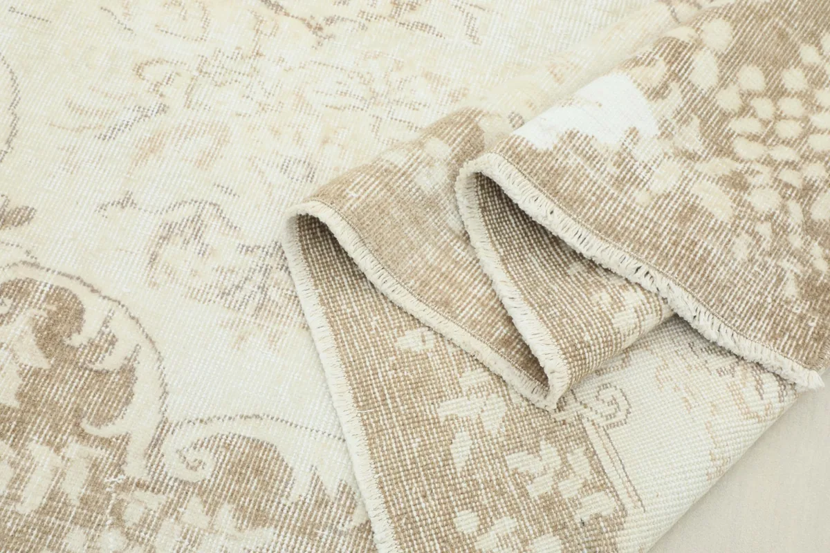 Rolled edge of the rug showing the thickness of the hand-knotted wool pile.