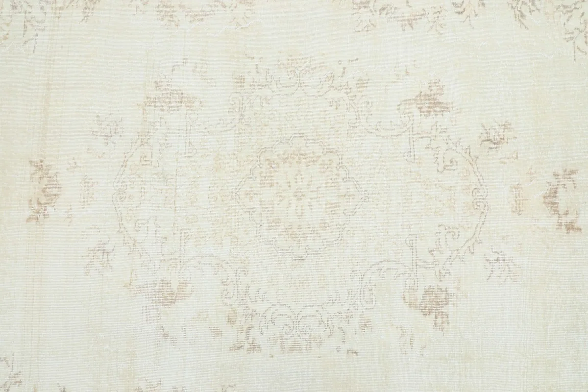Overhead detail showing the faded floral and medallion patterns in cream and beige tones.