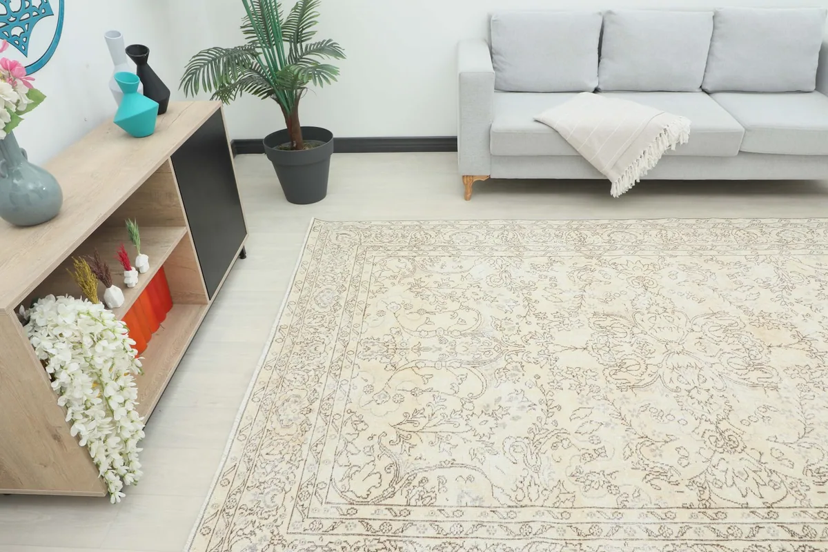 Angled view of the large ivory and tan vintage rug in a room, showing its scale.