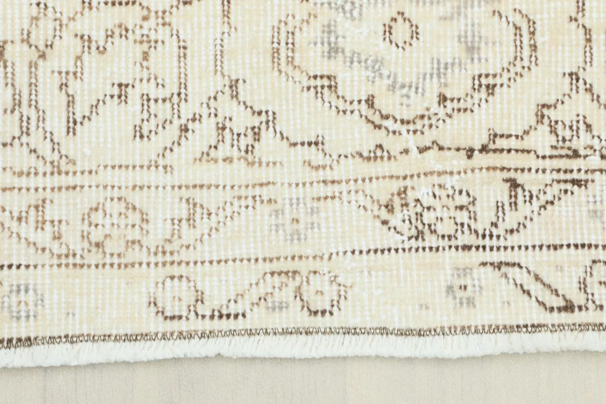 Close-up view of the rug's border showing the tan floral patterns and fringe detail.