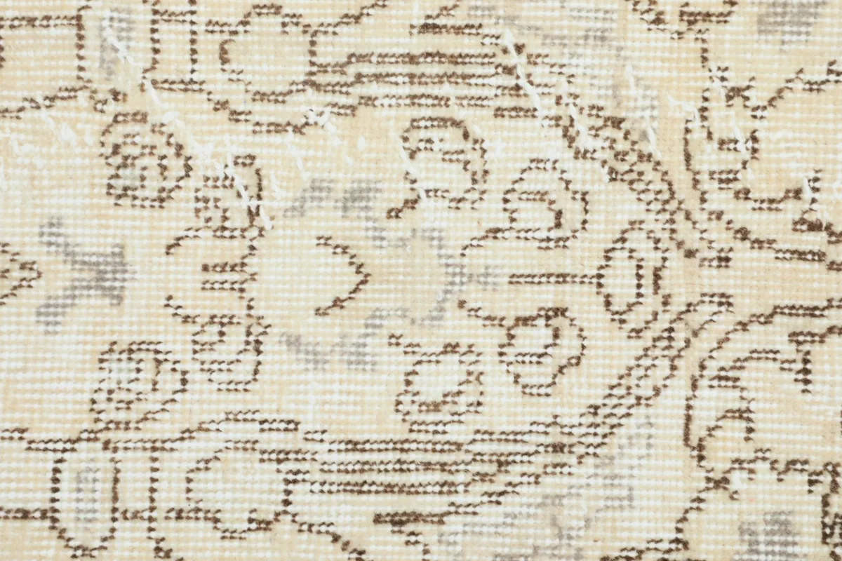 Close-up showing the low wool pile and hand-knotted texture with tan details.