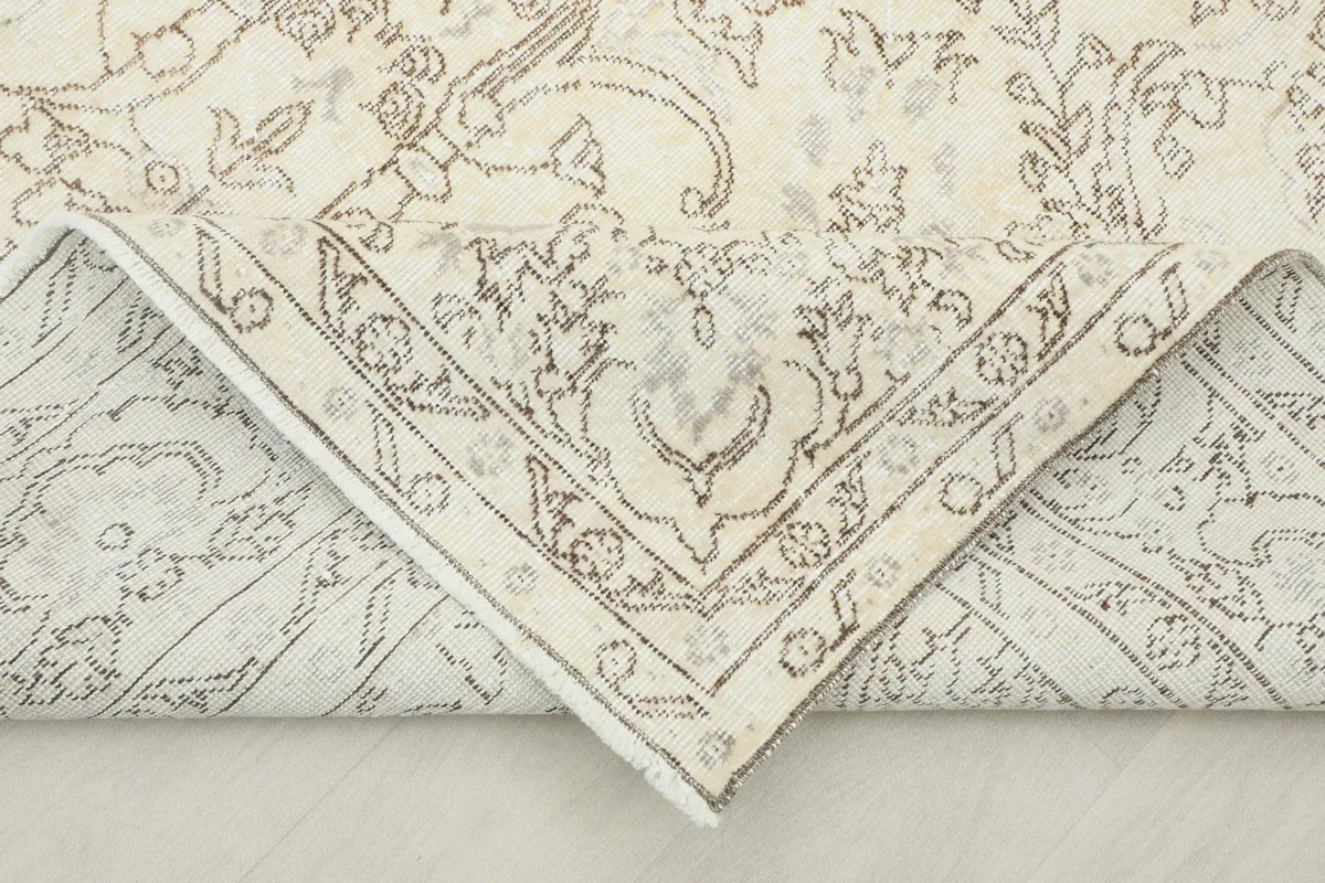Flipped corner of the rug revealing the cotton foundation and reverse side of the hand-knotting.