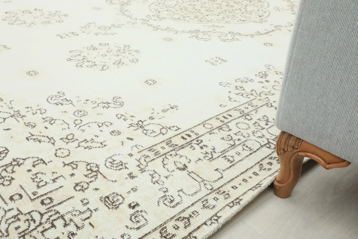 Rug placed under a sofa, showing a portion of the border and field pattern next to furniture leg