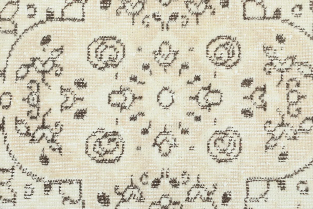 Close-up of a floral motif within the rug, highlighting the beige and brown wool pile