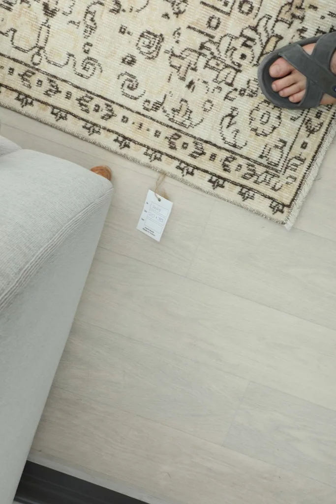 Overhead view of a section of the rug, showing a tag and a person's foot nearby for scale