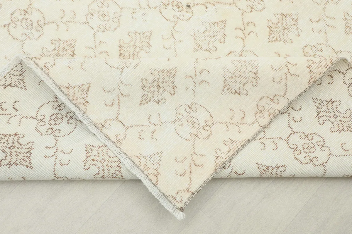 Corner of the rug folded back to reveal the cotton foundation and the reverse side of the hand-knotting.