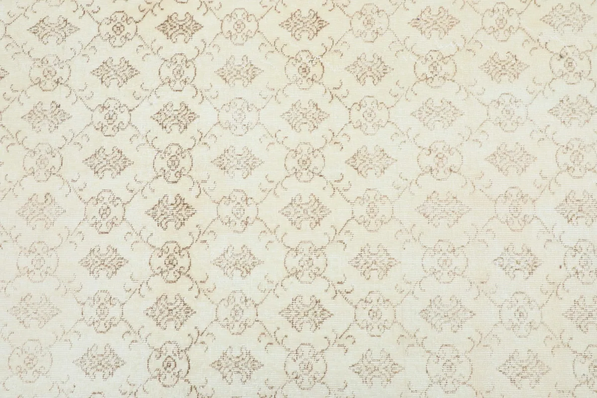 Overhead view showing the full repeating geometric and floral pattern across the cream field of the rug.