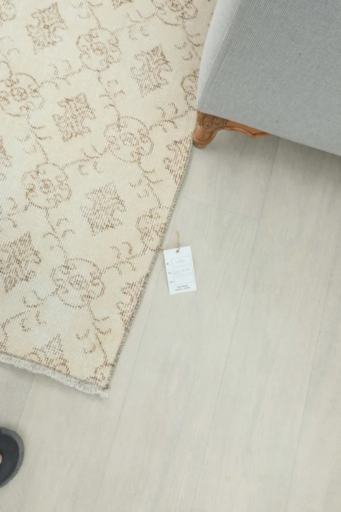 Overhead view of a corner of the rug on a light floor, with a product tag visible next to it.