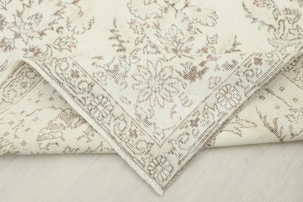 Corner of the rug folded back, revealing the reverse side and knotting.