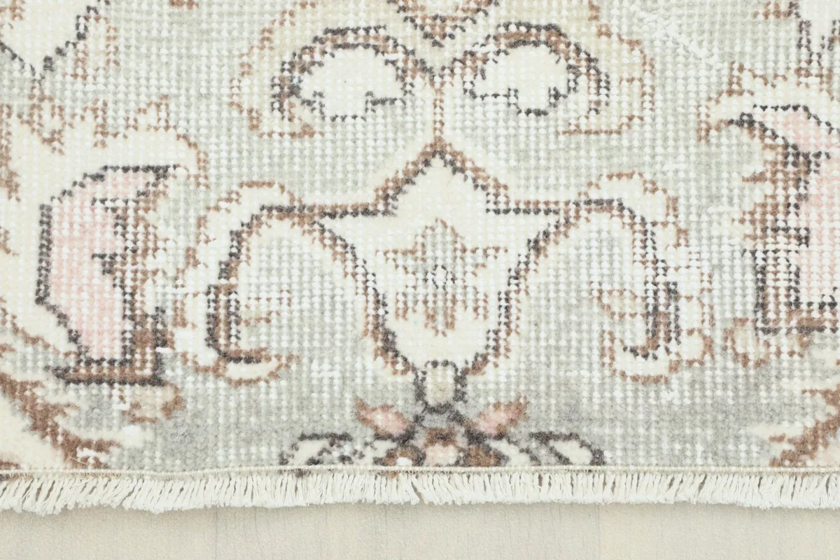 Close-up of the rug's low pile and intricate medallion motif in cream, gray, brown, and pink
