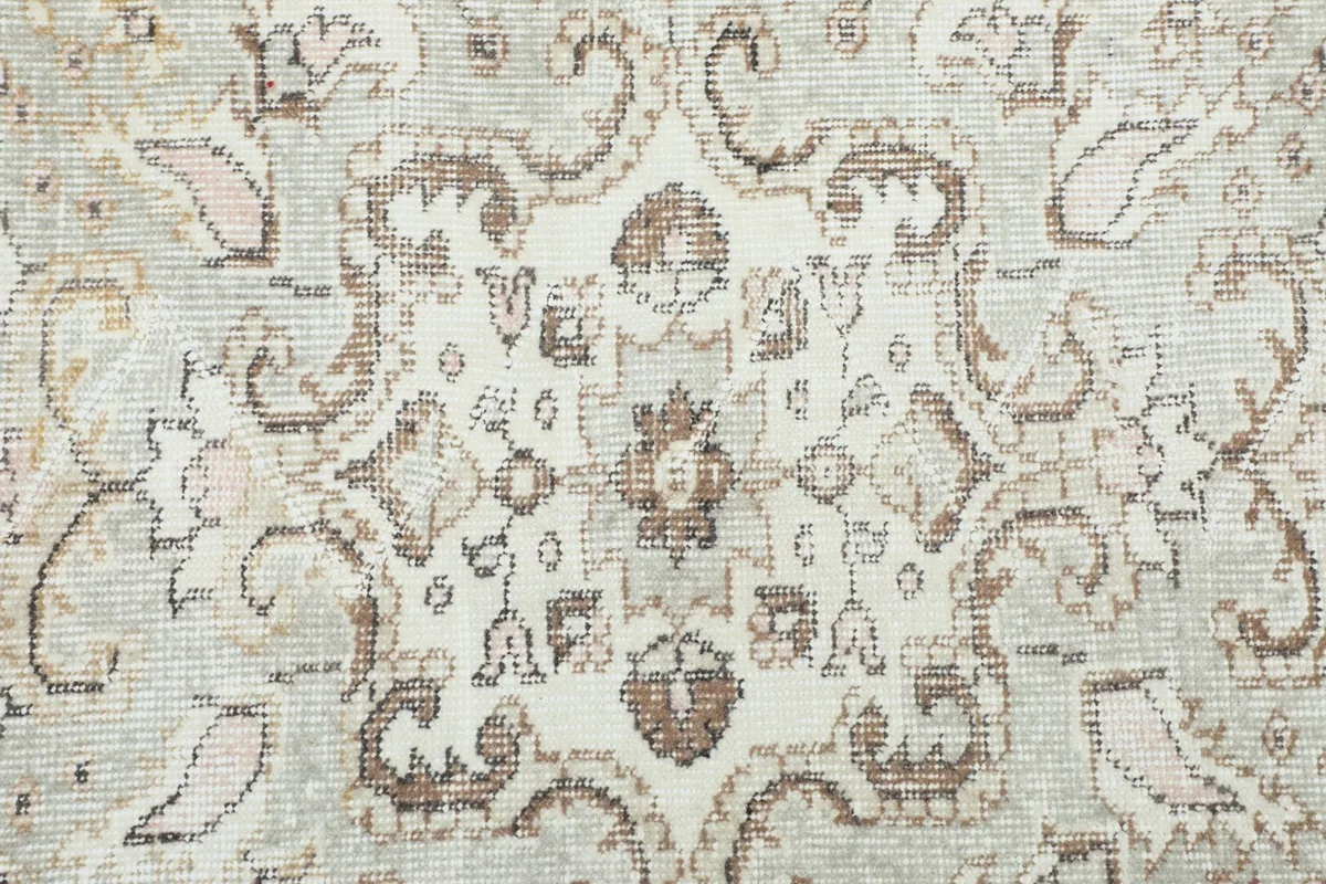 Detailed view of the faded floral and geometric motifs within the rug's field
