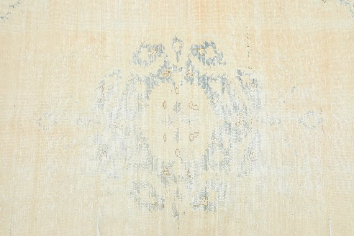 Detail view of the faded central floral medallion pattern on the ivory field