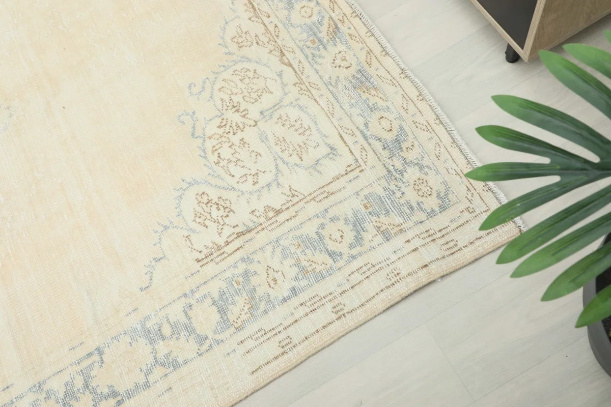 Detailed view of the blue and beige floral border design on the vintage wool rug