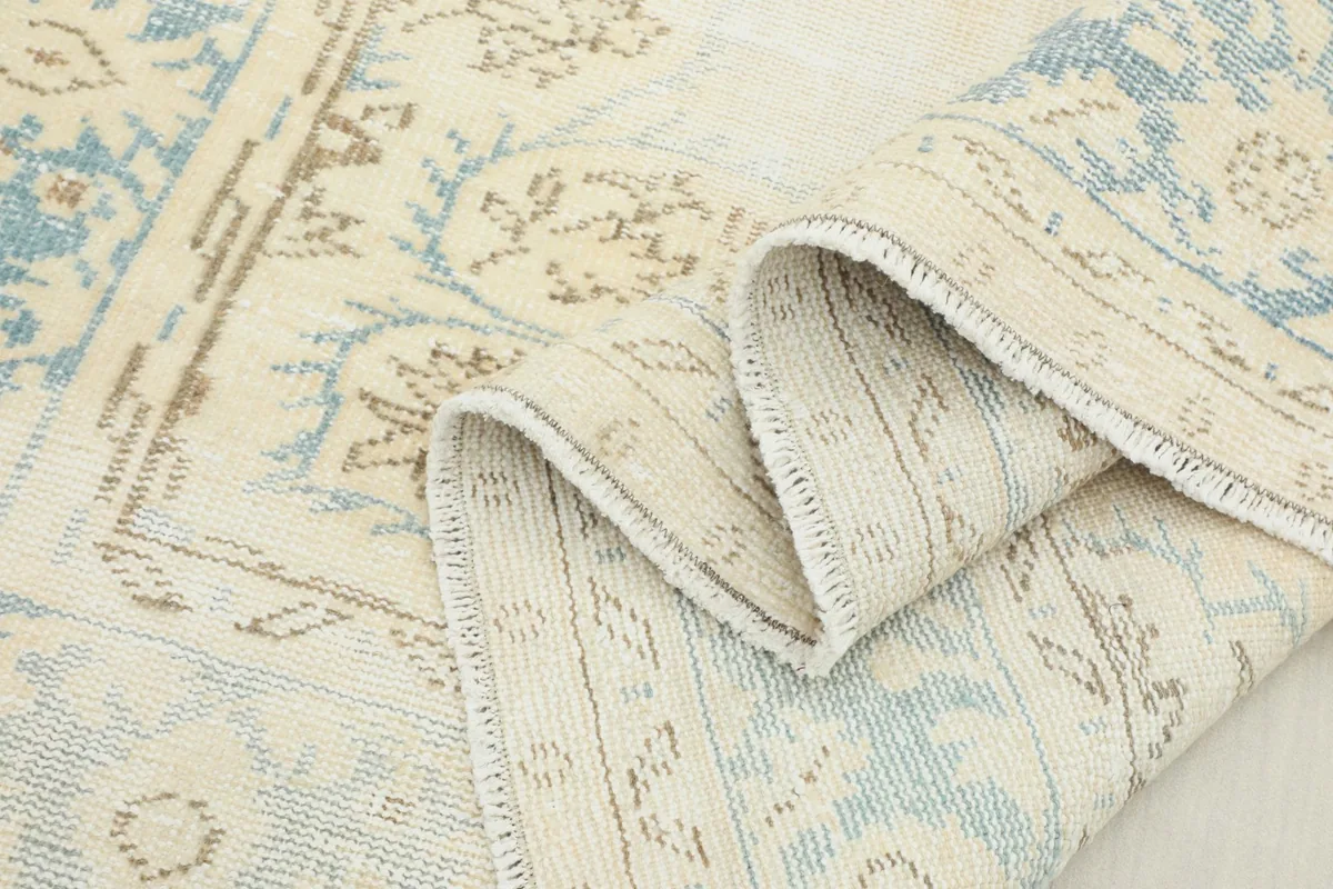 Folded section of the rug highlighting the texture and faded blue and beige patterns