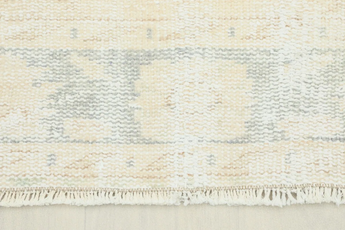 Close-up view of the rug's short fringe and a section of the faded border pattern