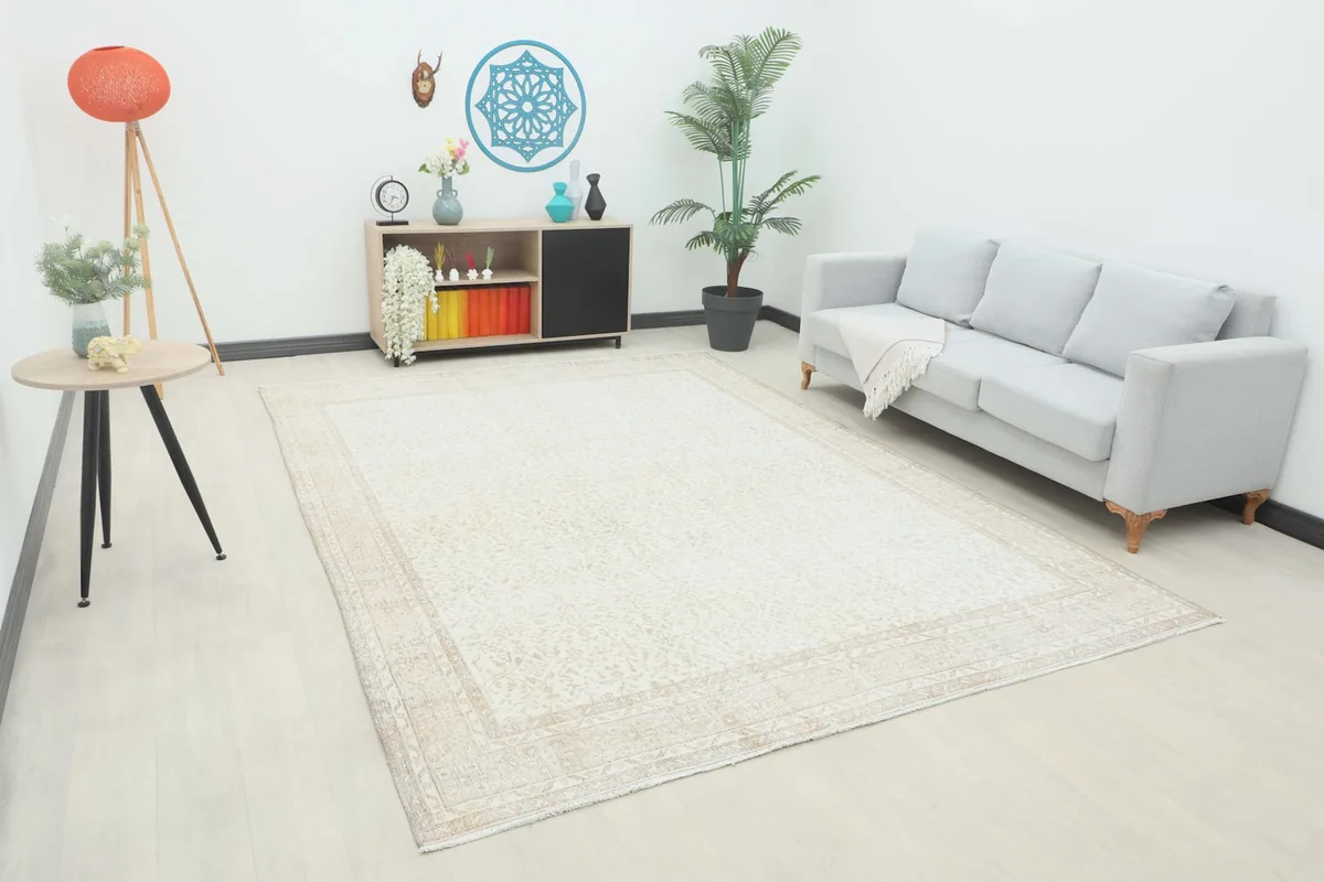Ivory and beige vintage rug displayed in a bright living room setting with a light sofa