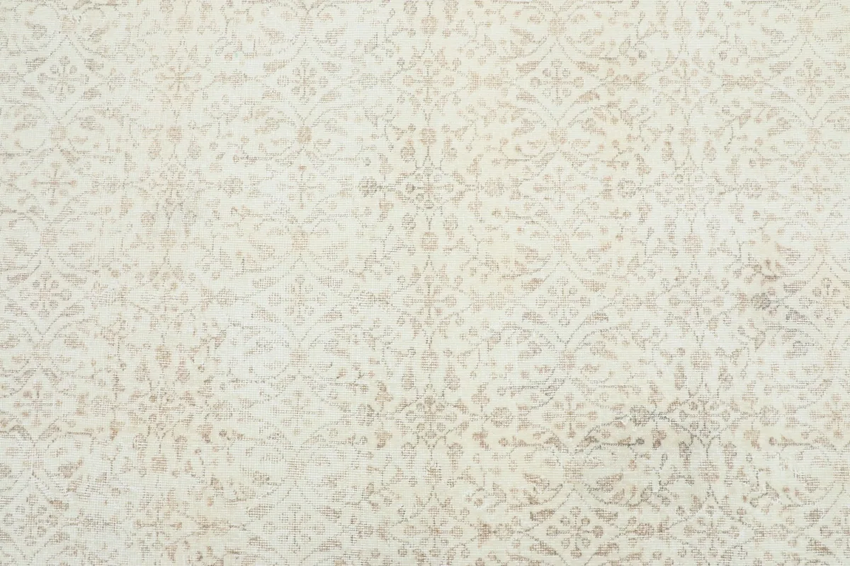 Detailed overhead shot of the rug's ivory field with subtle beige floral patterns