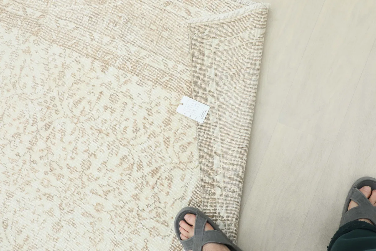 View of the rug with a tag, showing its texture and color variation under natural light