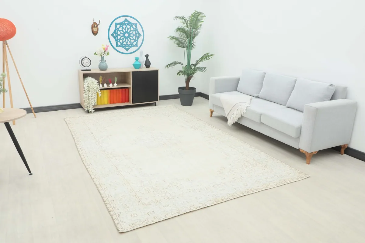 Ivory area rug displayed in a living room setting with a light gray sofa